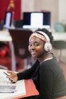 Retrato estudante feminino confiante com fones de ouvido e telefone inteligente — Fotografia de Stock