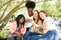 Щасливі друзі-жінки, використовуючи смартфон у парку — стокове фото