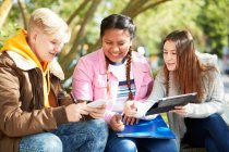 College students with digital tablet studying in sunny park — Stock Photo