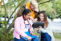 College students with digital tablet studying in park — Stock Photo