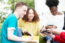 College students studying and using digital tablet in park — Stock Photo
