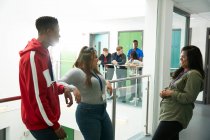 Студенты колледжа разговаривают и смеются в коридоре — стоковое фото