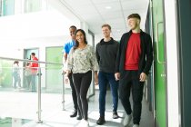 Studenti universitari a piedi in corridoio soleggiato — Foto stock