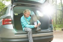 Mädchen bereitet sich auf Wanderung im hinteren Teil des Autos vor und bindet Schuhe — Stockfoto