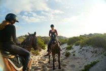 Young women horseback riding on sunny beach — Stock Photo