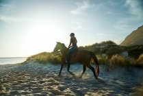 Jovem mulher cavalgando na praia tranquila ensolarada — Fotografia de Stock
