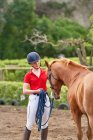 Дівчина-підліток в кінному шоломі навчає коня — стокове фото