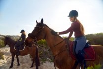 Молодые женщины верхом на лошадях на пляже — стоковое фото