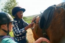 Girls adjusting stirrups for horseback riding — Stock Photo