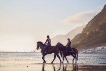 Young women horseback riding on tranquil ocean beach — Stock Photo