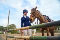 Ragazza adolescente in casco equestre con cavallo a ostacolo nel paddock — Foto stock