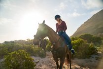 Jovem mulher cavalgando na praia ensolarada — Fotografia de Stock