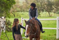 Female instructor teaching horseback riding to girl in rural paddock — Stock Photo