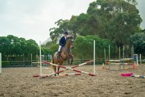 Teenage girl equestrian jumping in paddock — Stock Photo