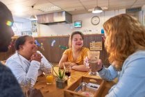 Young women with Down Syndrome talking with mentors in cafe — Stock Photo