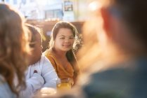 Портрет улыбающейся молодой женщины с синдромом Дауна в кафе с друзьями — стоковое фото