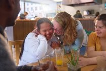 Mentor feliz e mulheres jovens com síndrome de Down rindo no café — Fotografia de Stock