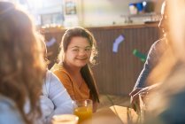 Счастливая молодая женщина с синдромом Дауна с друзьями в кафе — стоковое фото