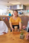 Портрет щасливої молодої жінки сервер з синдромом Дауна працює в кафе — стокове фото