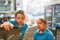 Young women with Down Syndrome working in cafe — Stock Photo