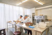 Chef e alunos com Síndrome de Down assar na cozinha restaurante — Fotografia de Stock