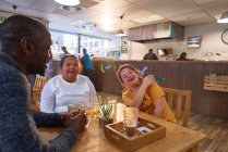 Felices jóvenes amigas con Síndrome de Down riendo en la cafetería - foto de stock