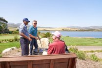 Друзья-гольфисты говорят, что пьют пиво на солнечном патио поля для гольфа — стоковое фото