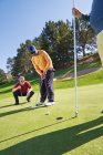 Golfista masculino colocando em verdes ensolarados golfe — Fotografia de Stock