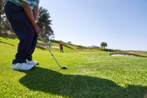 Golfista masculino tomando um tiro no campo de golfe ensolarado — Fotografia de Stock