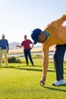 Male golfer preparing to tee off at sunny golf tee box — Stock Photo