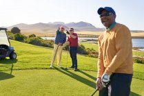 Golfeurs masculins parlant sur le terrain de golf ensoleillé — Photo de stock