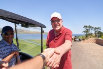 Perspectiva pessoal golfistas masculinos aperto de mão no campo de golfe ensolarado — Fotografia de Stock