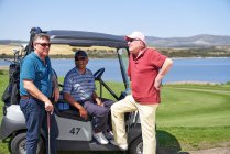 Счастливые взрослые гольфисты разговаривают на солнечной гольф-карте — стоковое фото