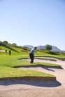 Golfista maschio che si prepara a prendere un colpo sopra bunker campo da golf soleggiato — Foto stock