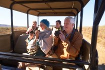 Щасливі літні люди з біноклями і фотоапаратом на сафарі в позашляховику — стокове фото