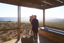 Casal sênior com câmera na varanda ensolarada cabine safari — Fotografia de Stock