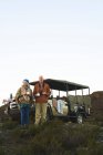 Casal sênior no safari bebendo chá fora do veículo off-road — Fotografia de Stock