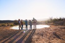 Safari tour guide and group at water in sunny grassland South Africa — Stock Photo