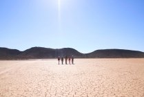 Safari grupo de turistas caminando a lo largo de la soleada tierra agrietada Sudáfrica - foto de stock