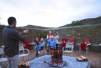 Старші друзі з вином позують для фотографії у вогняній ямі патіо — стокове фото
