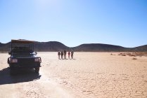 Safari grupo de turistas caminando en el soleado desierto árido de Sudáfrica - foto de stock