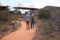 Heureux couple de personnes âgées marchant sur le sentier extérieur safari lodge — Photo de stock