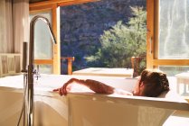 Gelassene Frau badet in sonnigem Hotelzimmer — Stockfoto