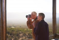 Coppia anziana con macchina fotografica sul balcone soleggiato safari — Foto stock