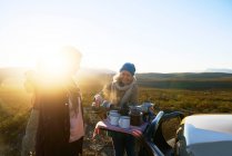 Happy senior woman on safari pouring tea for friend at sunrise — Stock Photo