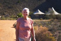 Porträt glückliche Seniorin auf sonnigem Fußweg vor Safari-Lodge — Stockfoto