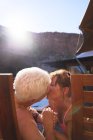 Счастливая романтическая старшая пара целуется на солнечном балконе — стоковое фото