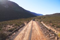 Safari позашляховик їде по сонячній віддаленій ґрунтовій дорозі Південної Африки. — стокове фото
