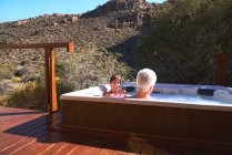 Feliz pareja de ancianos relajándose en la bañera de hidromasaje en el balcón del safari soleado - foto de stock