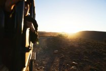 Veículos off-road Safari dirigindo ao longo da estrada de terra rochosa ao nascer do sol — Fotografia de Stock